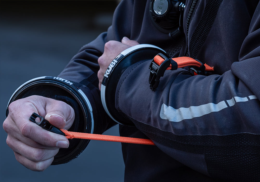 Diver in drysuit connecting a Remora webbing strap for a dive computer around their arm 